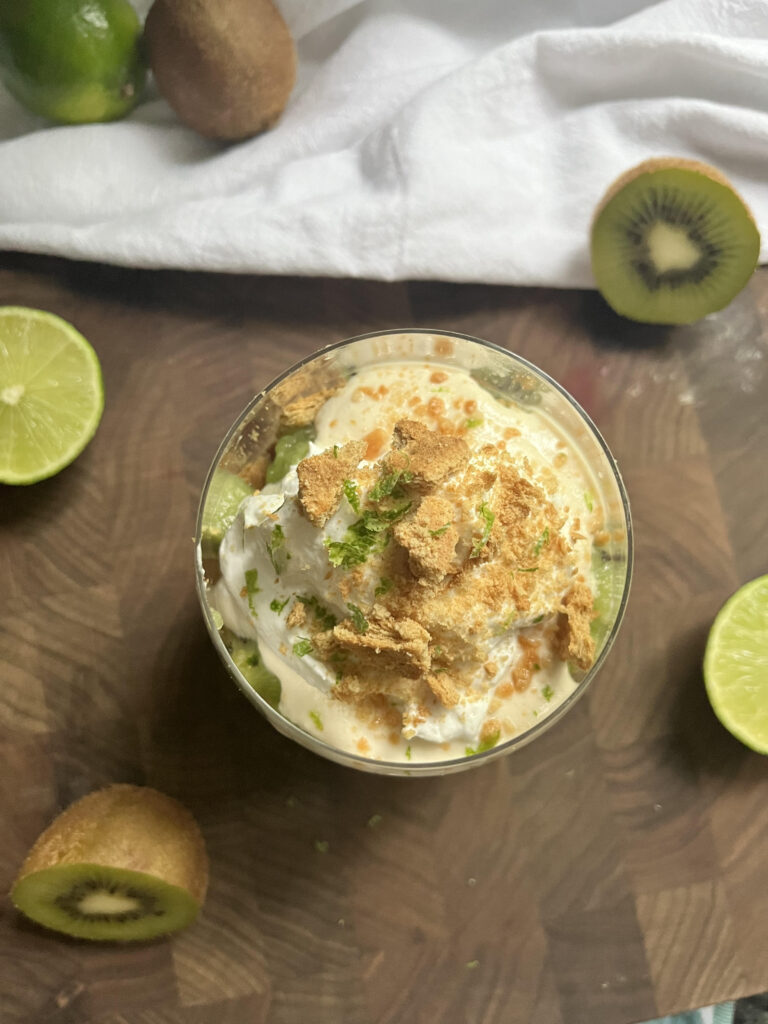 Kiwi lime pie parfait in a glass on a wooden cutting board