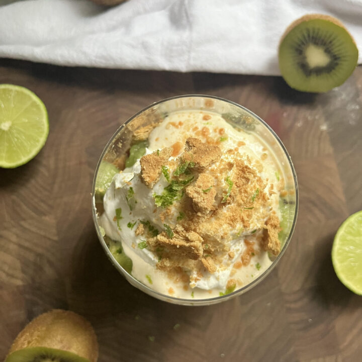 Kiwi lime pie parfait in a glass on a wooden cutting board